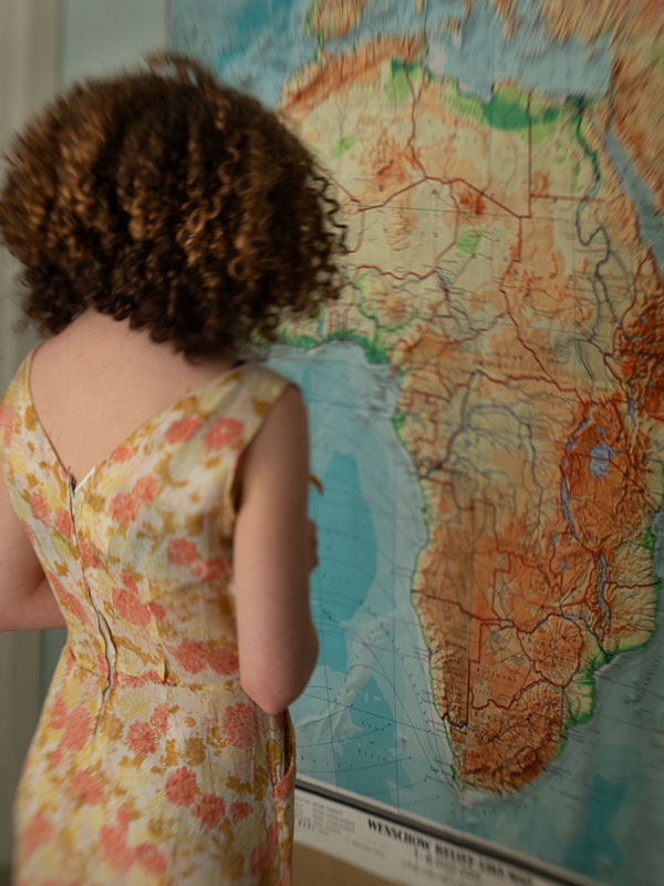 girl with curly hair and orange dress looking at map